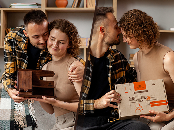 Two couples in a home setting, examining wooden boxes with designs. One pair looking at an open box, the other pair holding a closed box.