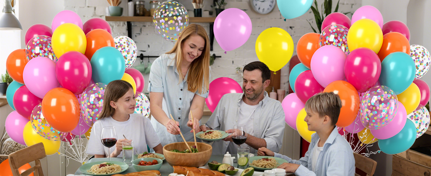 Festive dining scene with colorful balloon arch featuring pink, yellow, teal, and orange balloons creating celebratory atmosphere.