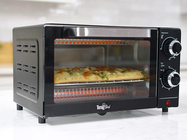 Total Chef toaster oven with food inside on a white marble counter with a plant beside it