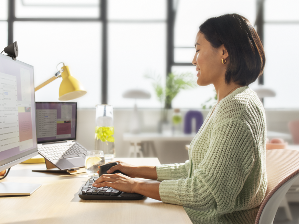 a woman typing on wave keys for business wireless ergonomic compact keyboard