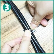 Hands demonstrating the use of a cable organizer or zipper-style cable management system on black cords against a light wooden surface.