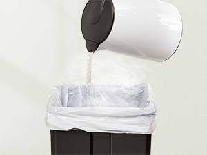 White trash bag being placed into a small waste bin. Liquid is being poured from a container into the bag.