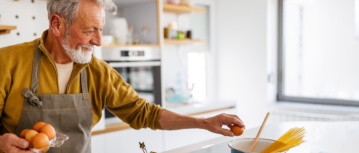 Senior man enjoying cooking with air fryer accessories