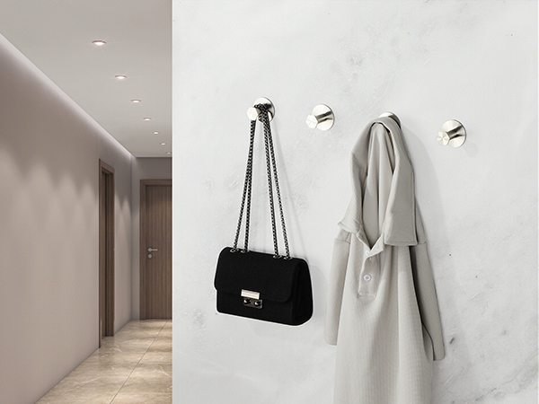 Hallway with white walls featuring three mounted coat hooks. A black handbag and white bathrobe are hanging on the hooks, demonstrating their use.
