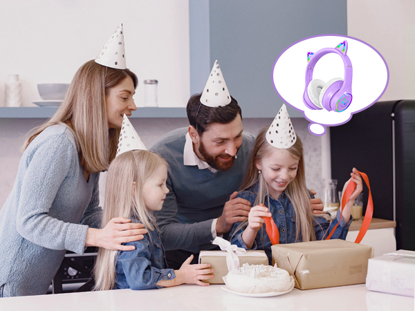 Family celebrating with party hats, cake, and presents. Thought bubble shows purple headphones, suggesting consideration of audio gift.