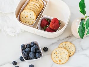 White square and rectanlge silicone baking cups in a lunch box with crackers and fruit