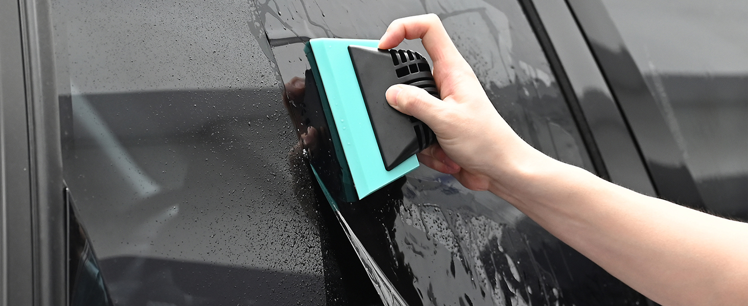 a hand scrubbing a car's windshield.