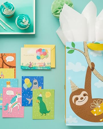 Kids birthday gift bag with sloth and colorful birthday cards with dinosaurs, unicorns and sharks