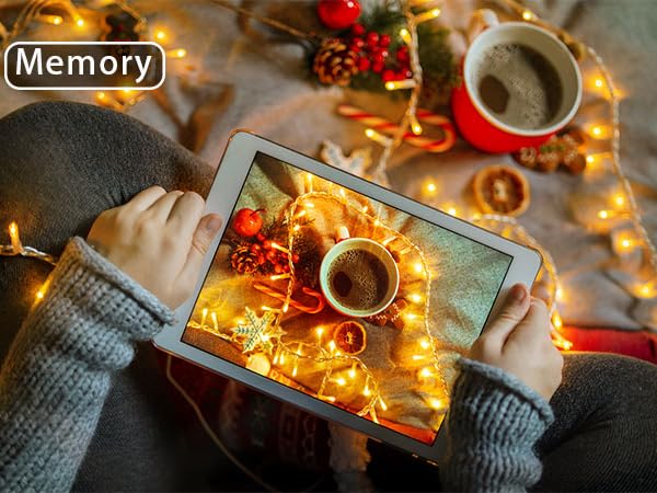 a person holding a tablet with christmas lights around them
