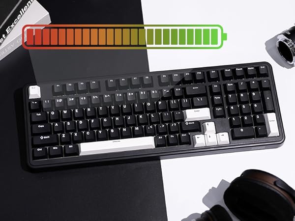 Black computer keyboard with white keys on a split black and white background. Colorful battery icon above. Partial views of other devices visible.