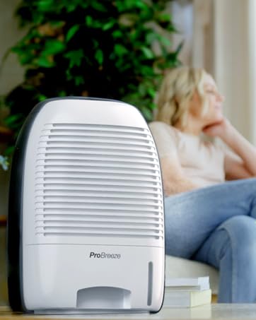 White portable dehumidifier with louvered front panel and water collection tank. Compact appliance for removing moisture from indoor air.