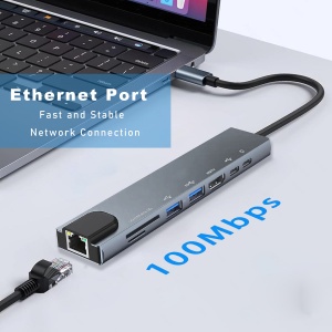 USB hub with multiple ports connected to laptop. Features Ethernet port and 1000Mbps speed. Gray rectangular device with cables attached.