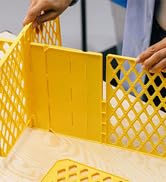 Two hands assembling yellow tote dividers on a wooden surface