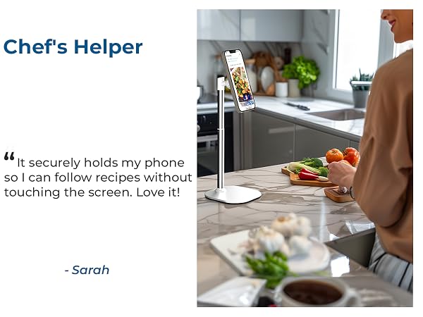 Adjustable phone holder mounted in kitchen setting, positioned above countertop. Demonstrates hands-free recipe viewing capability while cooking.