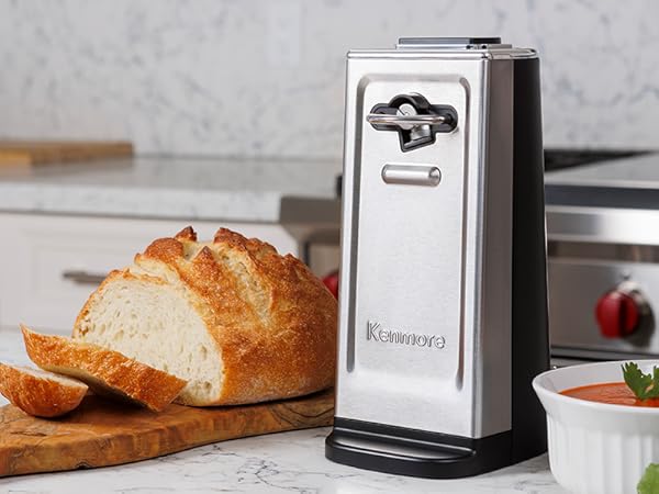 Kenmore smooth-edge can opener on a white marble countertop with a loaf of bread and bowl of soup