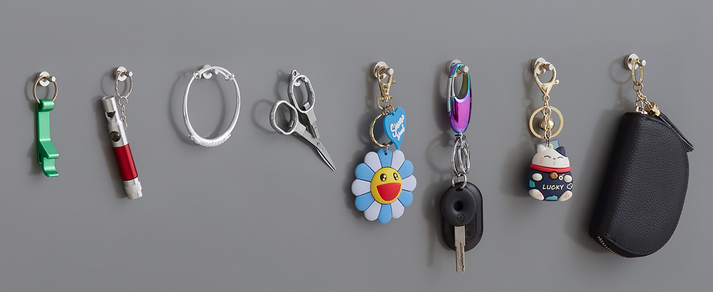 Collection of small decorative keychains and charms displayed on gray background, including floral designs, scissors, and various trinkets in different colors.