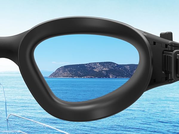 Close-up of black-framed swimming goggles. Lens shows clear view of an island in blue water, demonstrating clarity and field of vision.