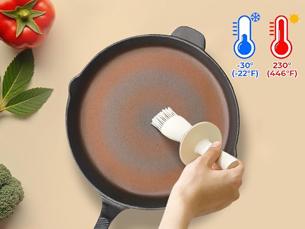 Round non-stick frying pan with temperature range icons showing -30°C to 230°C (-22°F to 446°F). Hand applying oil with a brush. Tomato and broccoli visible.