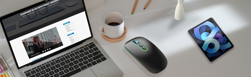 a mouse sits on a desk next to a laptop.