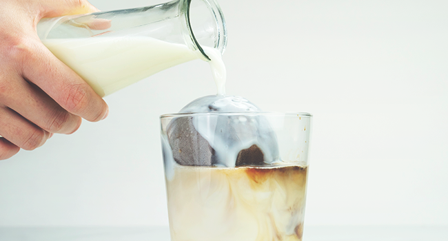 milk being poured into a glass with large iced coffee spheres made with silicone ice maker mold
