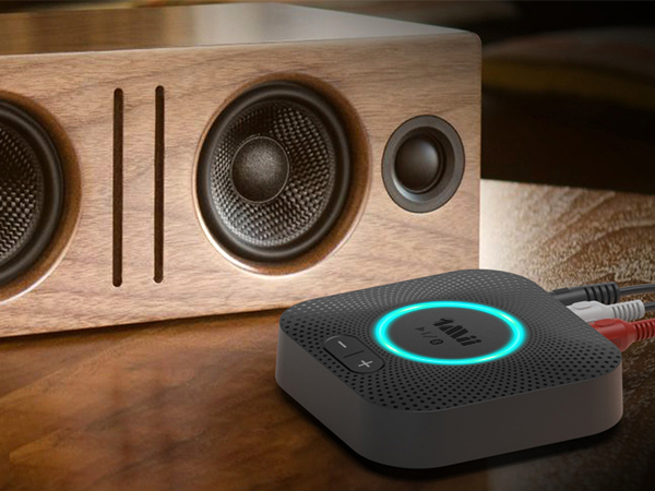 Close-up views of a modern black soundbar or speaker system with turquoise LED accent lighting, shown from multiple angles on a wooden surface.