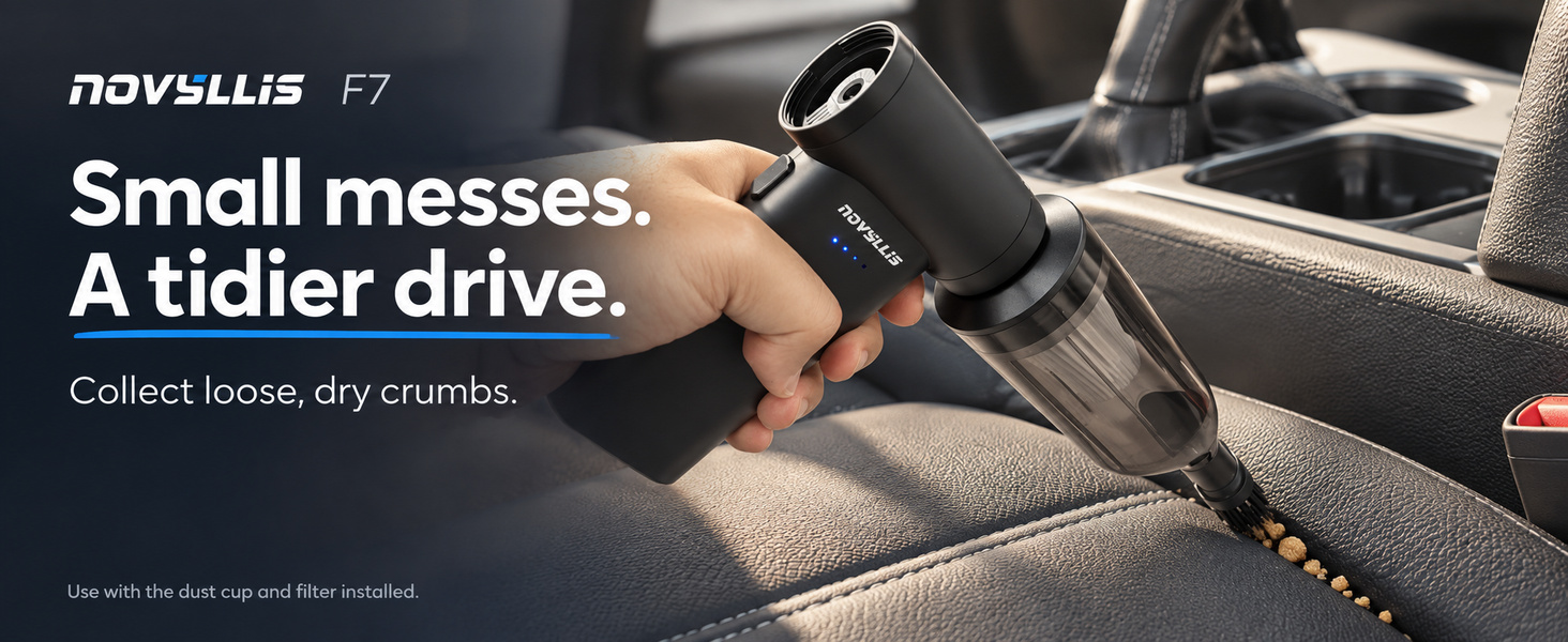 Handheld car vacuum collecting loose dry crumbs from a leather seat seam with a brush nozzle
