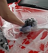 person scrubbing hood of red car with soapy sponge and car wash soap