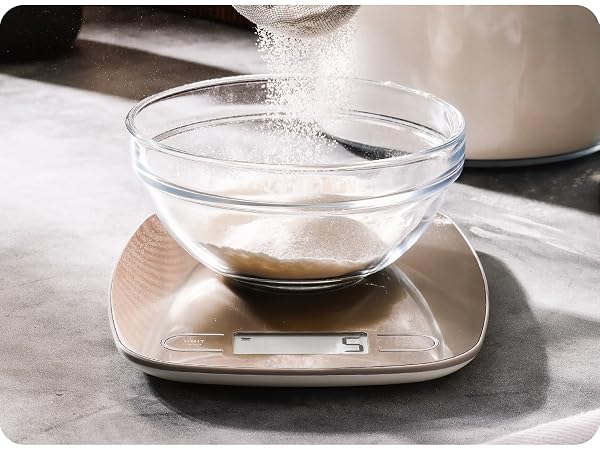 greater goods stainless steel kitchen scale on marble counter weighing bowl of powder sugar