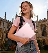 Young woman wearing pink t-shirt holding white laptop, standing in front of historic stone university building with Gothic architecture, wearing black backpack.