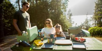 Family camping, cooking and eating in a picnic table