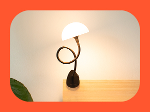 Modern table lamp with curved black stem and white dome shade, featuring a minimalist design against an orange background with a decorative leaf accent.