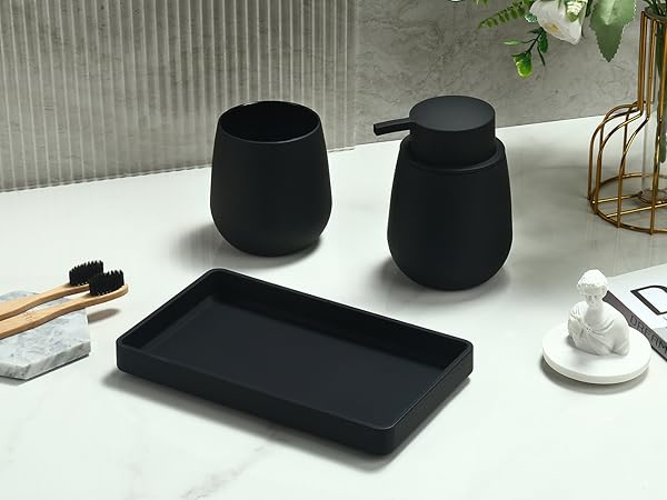 Black bathroom accessories set including two round containers, a rectangular tray, and wooden toothbrushes on a white surface. Minimalist design with matte finish.