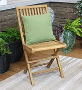 Teak folding patio chair on wooden deck with green pillow near potted plants and beige rug