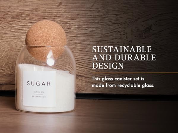 Glass storage container labeled 'SUGAR' with cork lid, displayed on wooden surface. Text indicates sustainable and recyclable glass construction.