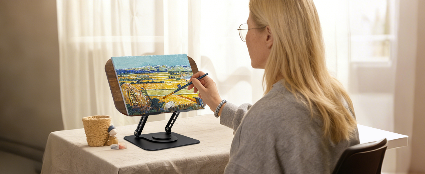 Person using laptop computer in sunlit room with ergonomic stand raising screen height for better posture.