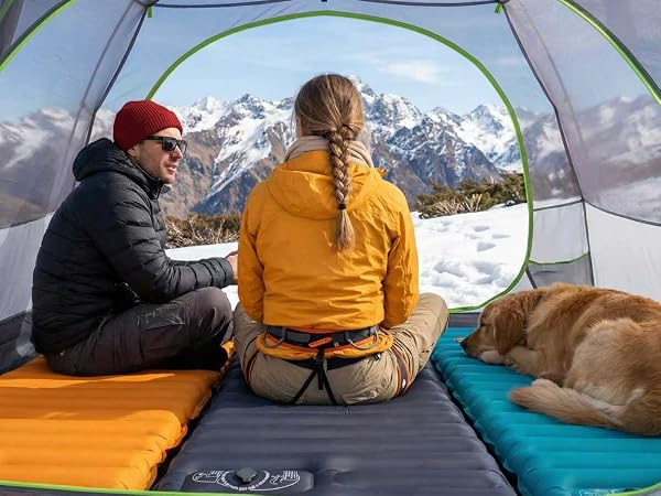 Couple and dog resting in tent on Airlive2000 pads with mountain view.