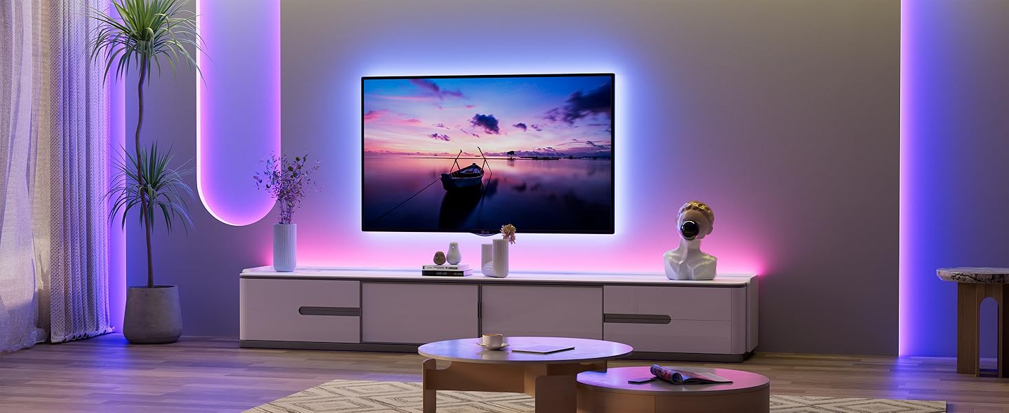 Modern living room with wall-mounted TV displaying sunset scene. White entertainment unit below. Ambient purple LED lighting behind TV and along walls. Round coffee table in foreground.