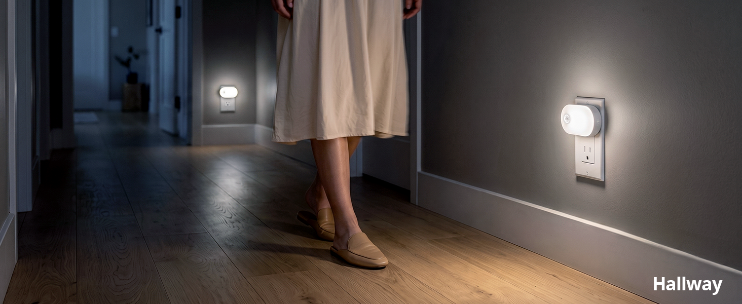 Plug-in night lights guiding a person walking down a hallway.