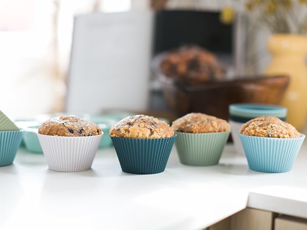 Free-standing silicone baking cups in white, navy, sage, and light blue with muffins in them
