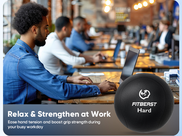 a man working at a desk with a laptop and a ball on it.