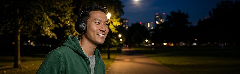 man outside wearing Sentry ANC headphone in a park at night