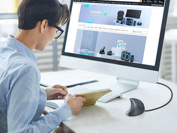 Modern ergonomic vertical mouse beside a computer monitor displaying an audio equipment website.