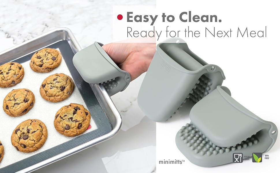silicone mitts holding a metal sheet with cookies