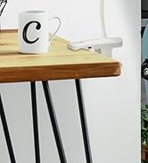 White desk power adapter or charging hub mounted underneath a wooden table surface with black metal legs. A white coffee mug visible on top.