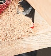 Close-up of woodworking in progress, showing wood shavings being created by a cutting tool on a light-colored wooden surface.