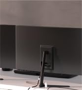 Black rectangular speaker or soundbar with a slim profile. Metal stand visible in front, suggesting it can be positioned vertically. Appears to be a home audio device.