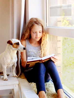 Girl with a dog reading by the window