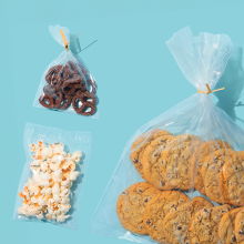 Three food-grade bags in different sizes being used to package cookies, popcorn, and pretzels