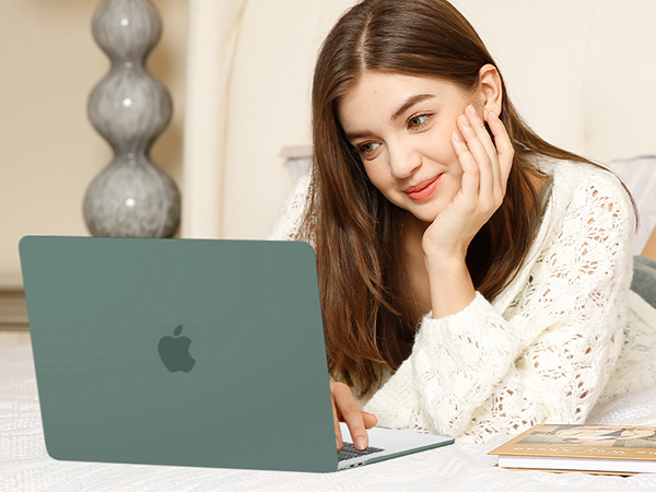 Green Apple laptop on white surface. Thin, sleek design with visible Apple logo on lid. Shown in use on table with papers nearby.