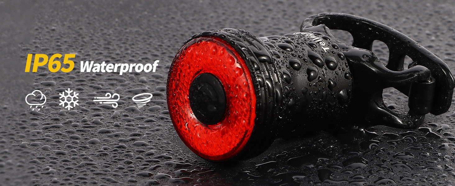 Waterproof bicycle tail light with bright red LED ring, shown wet with water droplets. Black body, IP65 rated for weather resistance. Includes mounting clip.
